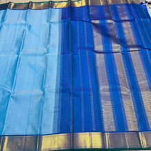 Nayaki- Beautiful Handwoven Pure Jari Kanjivaram Silk in a pastel blue with peacock blue combination with self striped body , rich mayilkan woven bawanchi borders rich seer pallu and contrast blouse