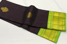 Vaibhogam- Gorgeous Deep Blackish Kanchana Brown with Parrot Green Handwoven Pure Jari Korvai with Buttas Kanjivaram Silk with beautiful double peacock motifs woven in a clover shaped motif with rich borders pallu and contrast woven blouse