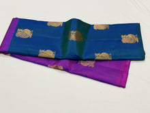 Saranga-Stunning Peacock Blue with Vadamalli Purple Handwoven Pure Jari Kanjivaram Silk in a half and half style woven body with muthukattam vertical stripes running thru the body with peacocks woven body rich pallu and contrast woven blouse.