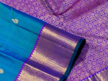 Vaibhogam- Stunning Peacock Bluish Green with Purple Handwoven Pure 2g Jari Kanjivaram Silk with beautiful buttas woven body rich mayilkan and thambalam buttas woven borders rich buttas woven pallu and contrast woven blouse with green selvedges
