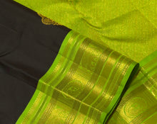 Vaibhogam- Gorgeous Deep Blackish Kanchana Brown with Parrot Green Handwoven Pure Jari Korvai with Buttas Kanjivaram Silk with beautiful double peacock motifs woven in a clover shaped motif with rich borders pallu and contrast woven blouse
