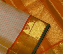 Sahana- Beautiful Biscuit beige with Orange Handwoven Pure Jari Kanjivaram Silk with muthukattam woven body with bawanchi temples and zigzags woven borders with green selvedges rich seer pallu and contrast orange blouse.