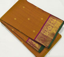 Sahana- Gorgeous Sampanga Mustard with Deep Magenta Buttas Handwoven Pure Jari Kanjivaram Silk with beautiful buttas woven body with mayil chakram motifs woven borders with green selvedges rich pallu and contrast woven blouse